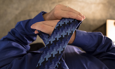 Overhead photo of a man tieing his tie.
