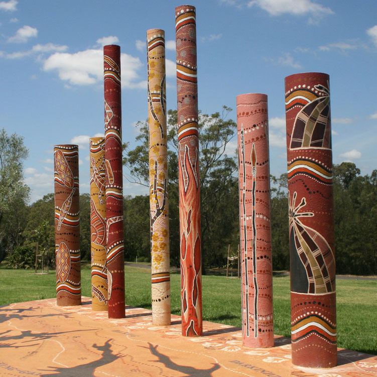 A photograph of The Seven Peace Keepers. Seven cylindrical statues in traditional aboriginal design and color.