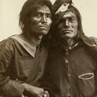 Two American Indian men sitting closely together.