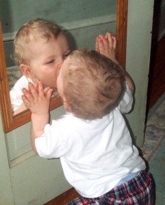 baby kissing his reflection in the mirror.