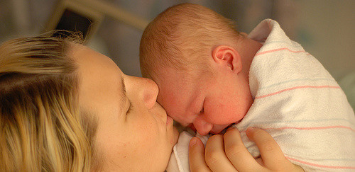 A caregiver cuddles an infant.