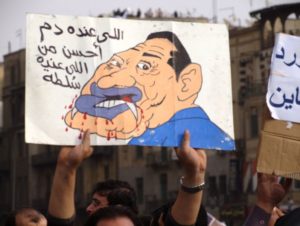 An Egyptian protester holds up a sign of Hosni Mubarak as a vampire