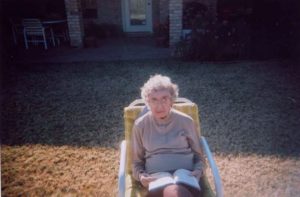 An elderly woman is sitting in a lawn chair