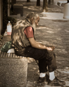An old homeless man sits on a bench in Boston