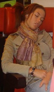 A woman is sleeping on a train.
