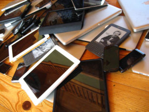A large number of tablets, phones, and e-readers are piled up