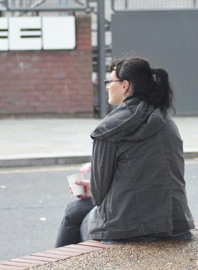 a woman sitting pensively on her own holding a coffee cup