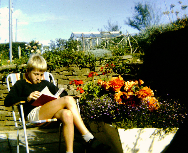 Child sitting outside, reading.