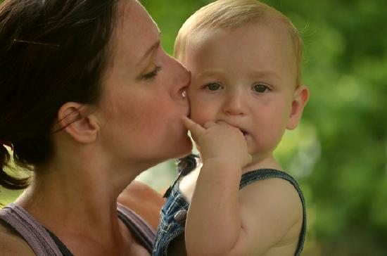 Mother kissing baby on cheek.