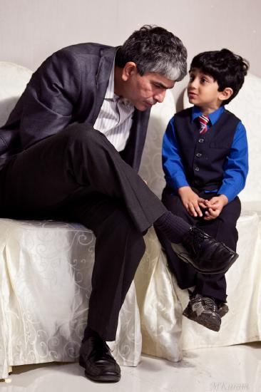A young child whispering in their father's ear.