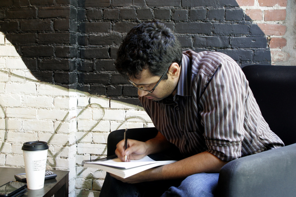 Photo of a male student writing in a notebook.