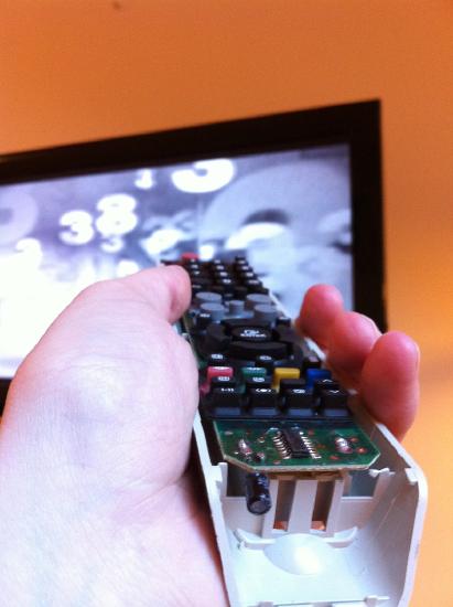 a hand holding a TV remote control
