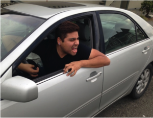 Photo of a guy leaning out a driver's side window of a car, yelling