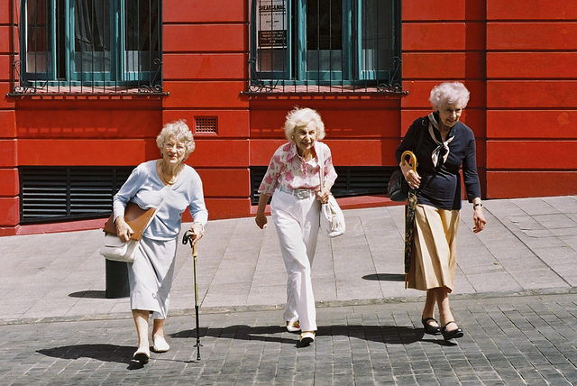 Three older people crossing a street.