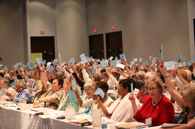 People raising their hands in a meeting.