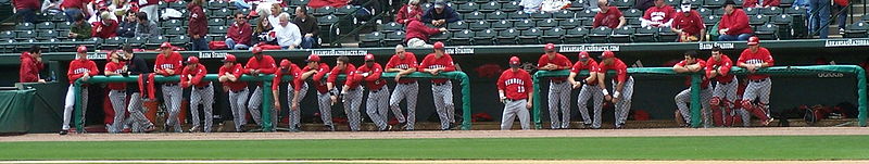 Photo of a group of baseball players hanging over the dugout wall, watching the game