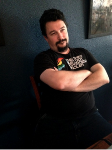 Photo of a guy leaning back in a chair, arms folded across his chest, with a smirk on his face.