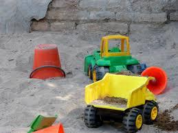 Tractores de juguete y cubos en una caja de arena