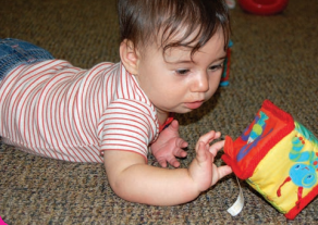 An infant looking at a cloth box tox