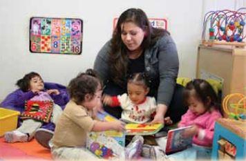 A caregiver reading to a group of toddlers