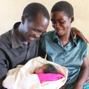 Un joven padre y una madre son todos sonrisas mientras sostienen a su bebé.