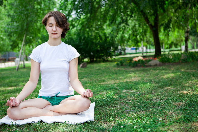 Una mujer medita en un parque.