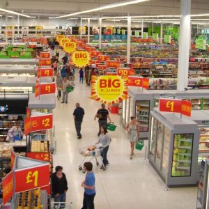 View of a modern supermarket with many aisles full of thousands of products and many hundreds of bright signs with product information.