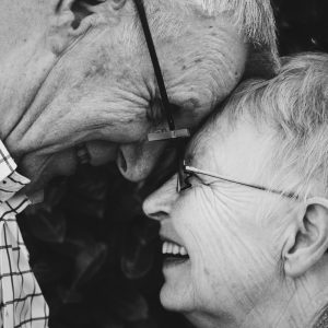Una pareja de ancianos se abrazan y se miran a los ojos.
