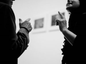 A man and woman are engaged in a conversation and making identical hand gestures.