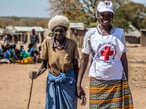 A Red Cross volunteer assists an elderly woman from Mozambique, where a food distribution was taking place.