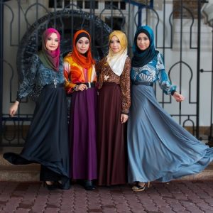 Un grupo de modelos de moda malasias posan con coloridos pañuelos en la cabeza, blusas de manga larga y vestidos hasta el suelo.