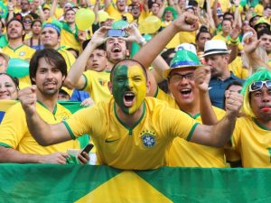Aficionados brasileños al fútbol vestidos con los colores de la selección nacional animan salvajemente desde las gradas durante un partido.