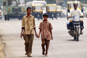 Dos chicos caminan juntos por una calle concurrida de Bangalore, India mientras se toman de la mano.