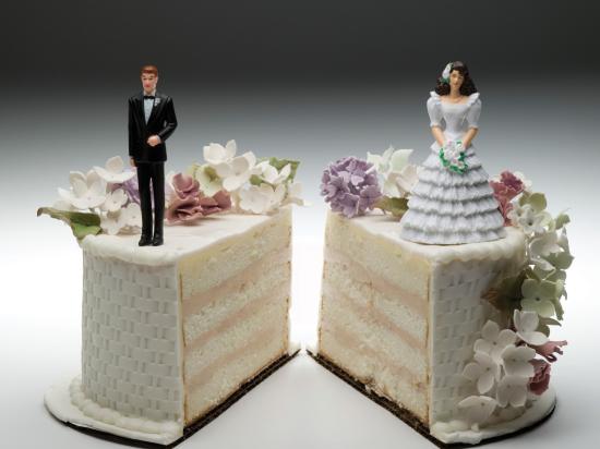 Wedding cake split into two separate halves, with a groom figurine standing on one side and a bride figurine standing on the other, symbolizing divorce or marital separation.