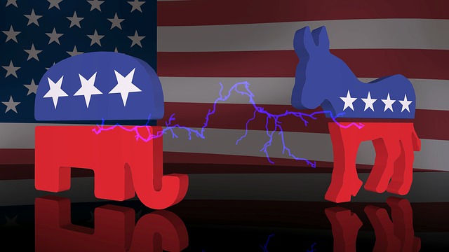 3D graphics of the elephant symbol of the Republican Party and the donkey symbol of the Democrat Party, both rendered in a single stripe each of red and blue and decorated with 3 white stars, sitting on a black field in front of a photograph of the U.S. flag. A bolt of lighting is crackling between the two animal figures.