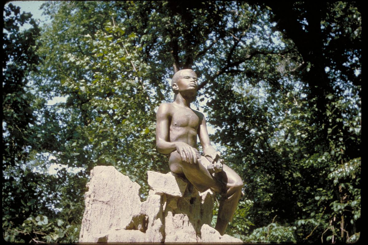 Bronze statue of George Washington Carver as a boy seated on a piece of rock, at the George Washington Carver National Monument in Missouri.