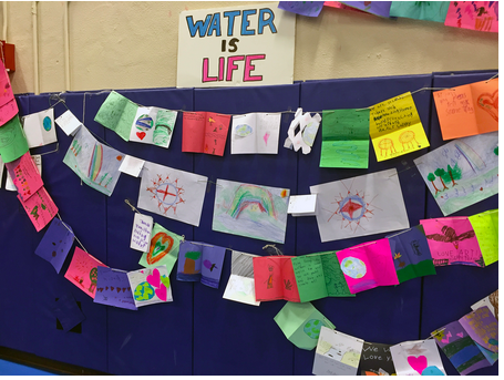 Letters and drawings from children displayed at Standing Rock Community High School, below a sign with the words "Water is Life", as part of the Dakota Access Pipeline protests.