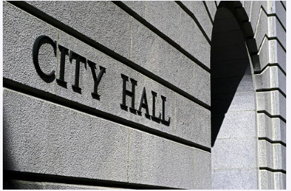 Photograph of an archway and wall made out of gray stone, with the words "City Hall" engraved in the wall. Image by Kevin Norris from Pixabay.