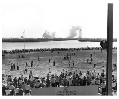 Black-and-white photograph of thousands of reporters watching the launch of the Apollo 11 moon mission on July 15, 1969 at the Kennedy Space Center, Florida.