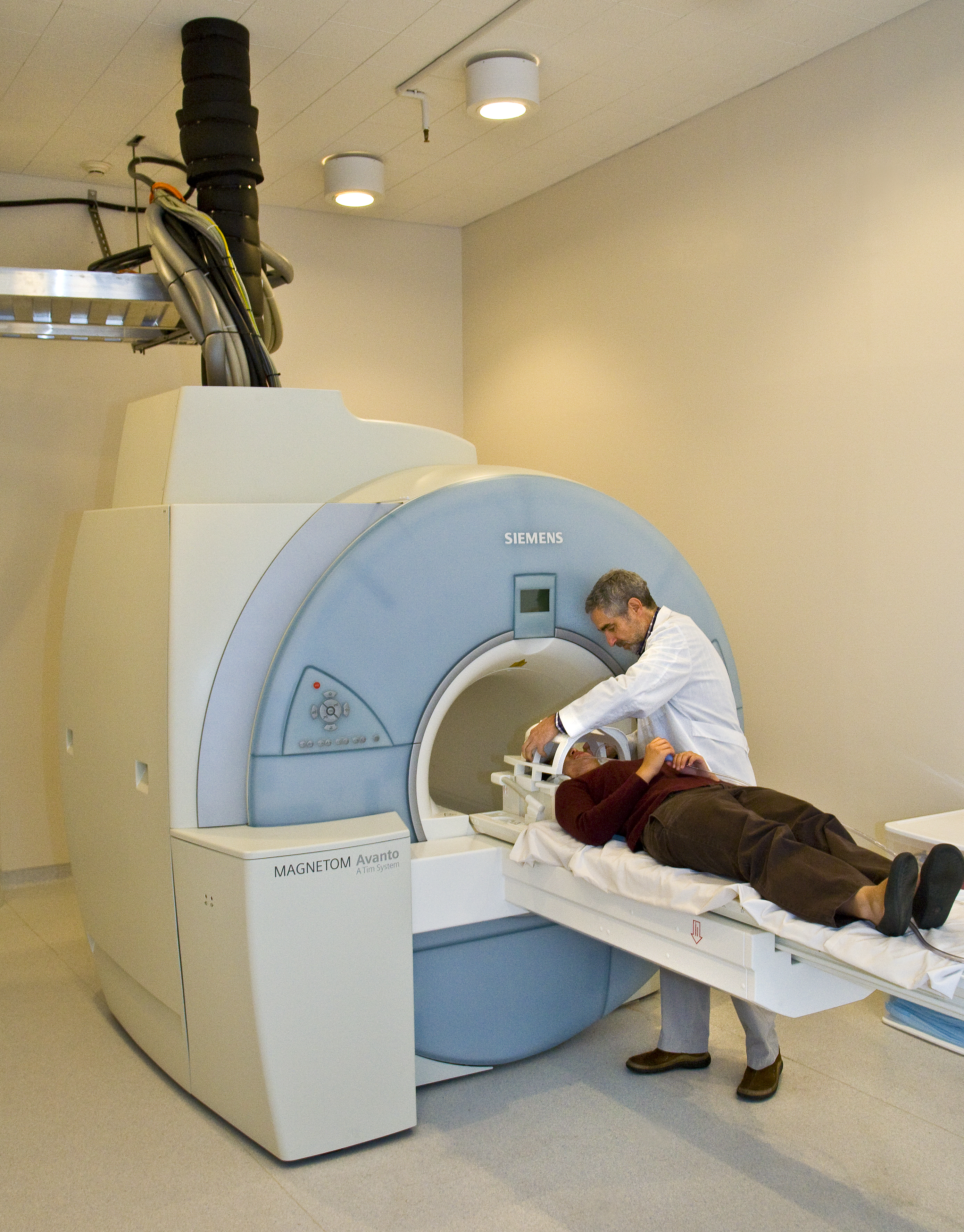 A doctor putting a patient into an FMRI machine. Patient is laying down. 