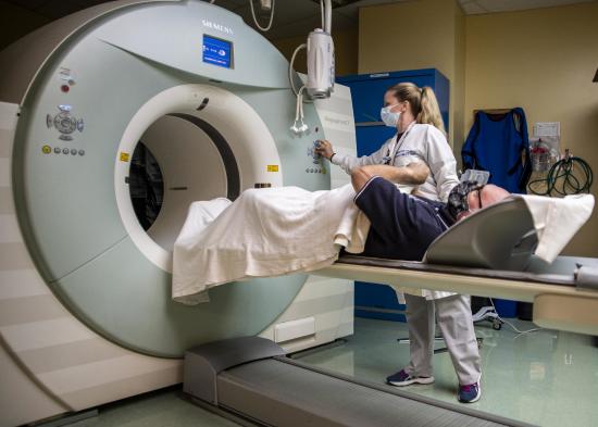 Doctor placing patient into a PET scanner. Patient is laying down.