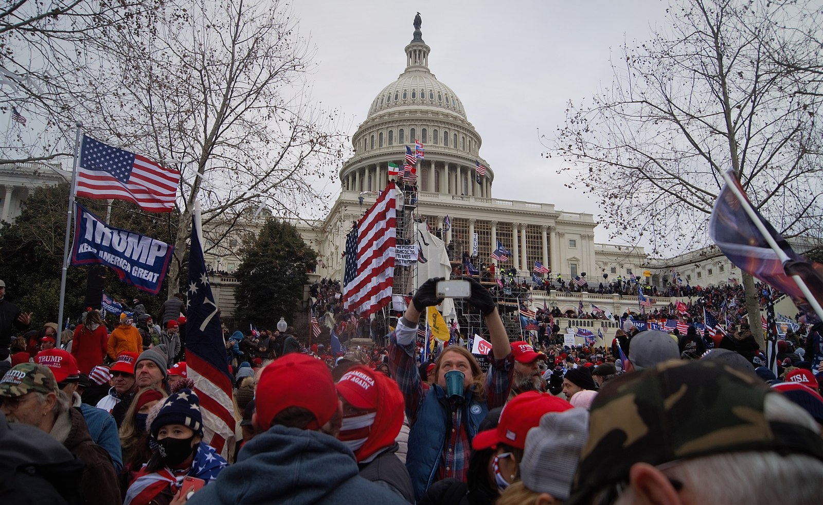 Photograph taken on January 6, 2021 of a large crowd rushing towards the U.S. Capitol, many of them waving banners or wearing hats with the messages "Trump" or "Make America Great Again."