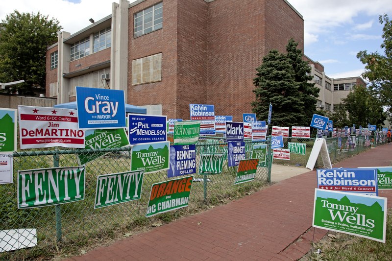 A number of campaign signs for local officials are hung on a chain-link fence outside the Hine Junior High School in Washington, D.C.