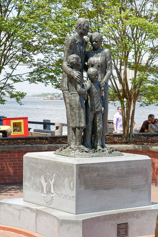 Monument in Savannah, Georgia composed of a bronze sculpture of an African American family (a father, mother, daughter, and son) standing on top of broken chains, atop a concrete pedestal engraved with ocean waves and chained hands. Monument designed by Dorothy Spradley, photograph by Judson McCranie.