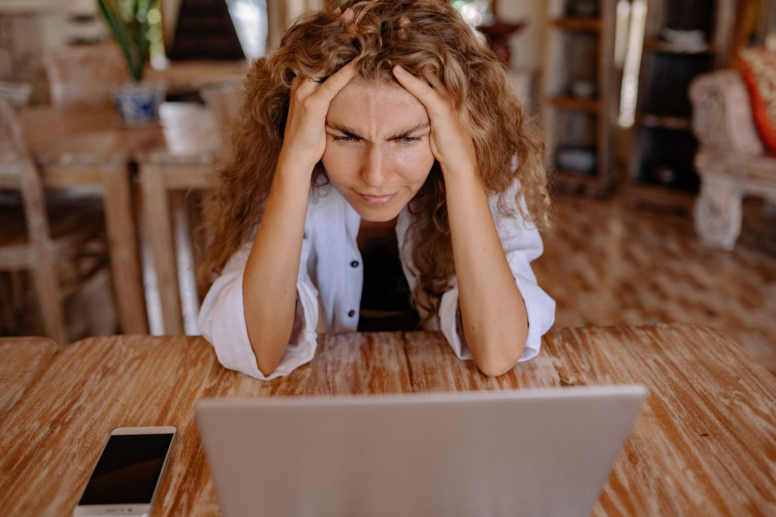 Mujer mirando laptop, con las manos en la cabeza, mirando estresada