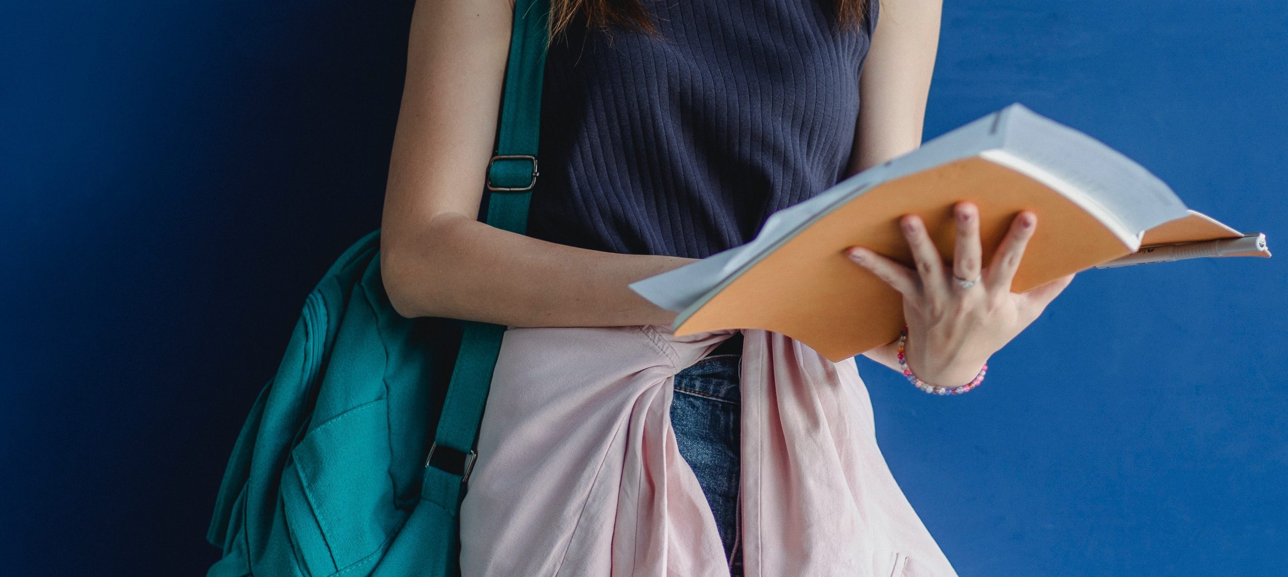 Mujer sosteniendo libro con mochila en hombro
