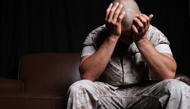 Marine seated with his head in his hands, suffering from PTSD.
