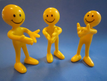 Three toy figures with happy faces clapping their hands.