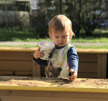 One year old toddler exploring sand