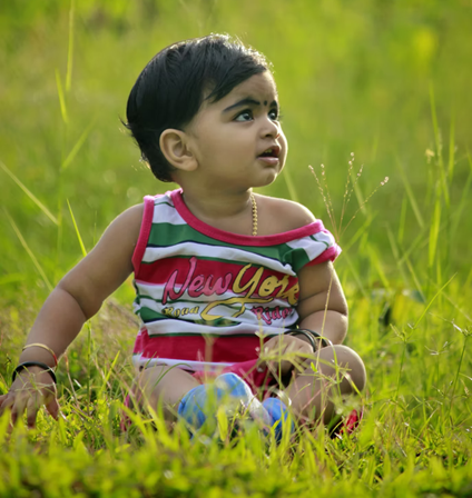 Niño explorando la hierba mientras está sentado afuera